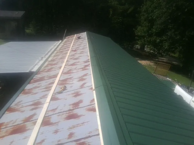 Old rusted panels beside newly installed green metal roofing — Wind Damage Roof Repair by Roofing Brothers in Campbell