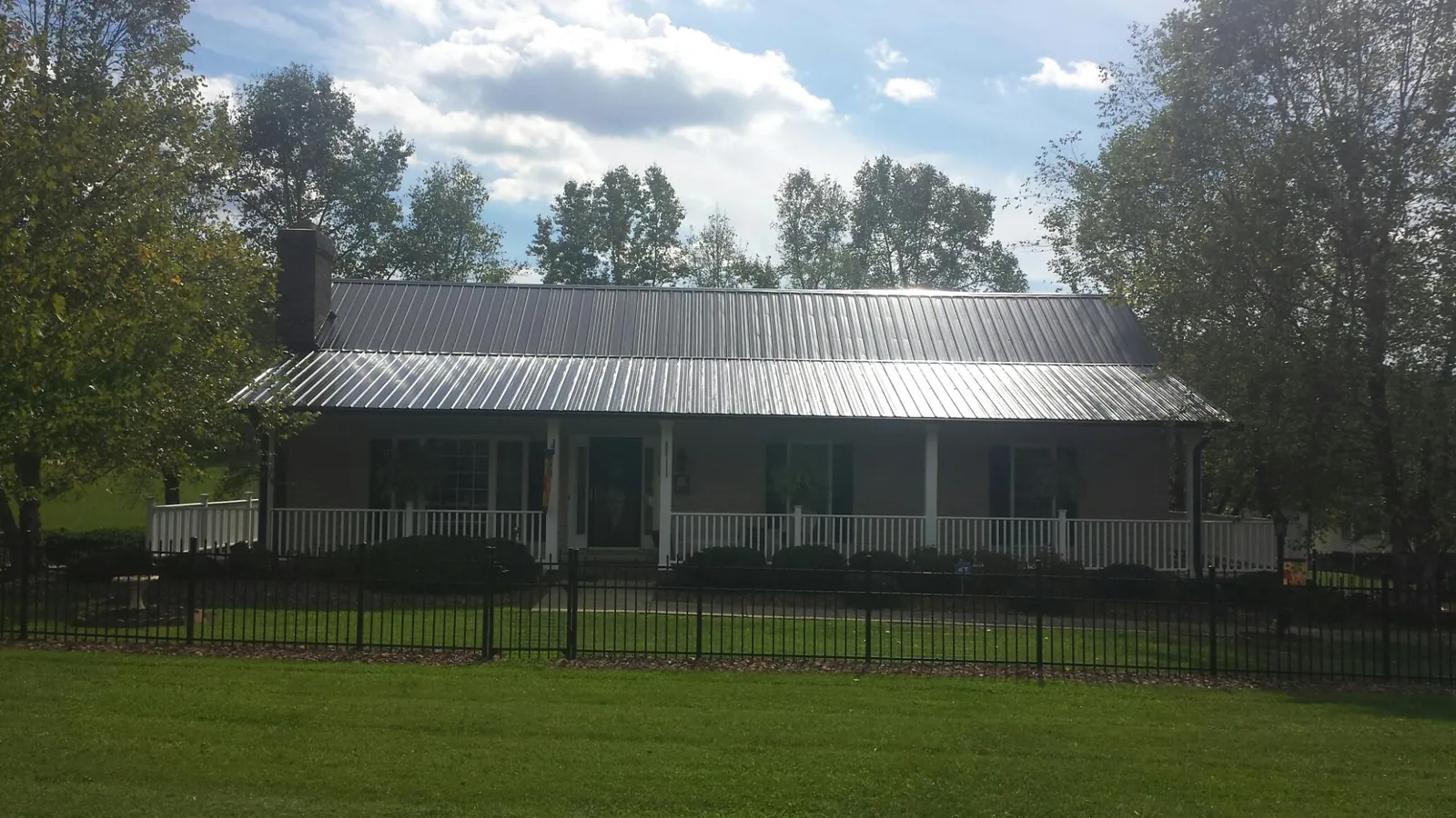 Gray metal roof on a brick ranch with a full width front porch — Gutter Guard Installation work by our crew in Campbell